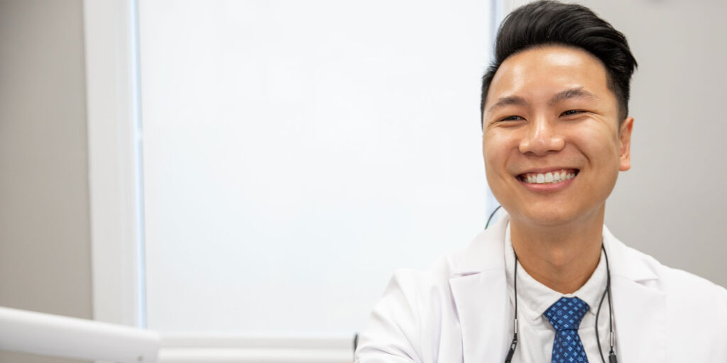 Doctor smiling holding a model of dental implants