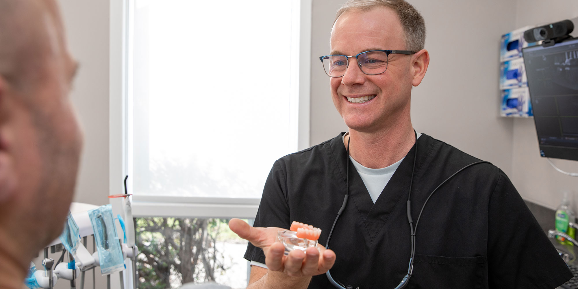 Doctor holding up a model of dental implants